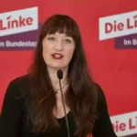 Heidi Reichinnek spricht vor einem roten Hintergrund mit dem Logo der Linken.
