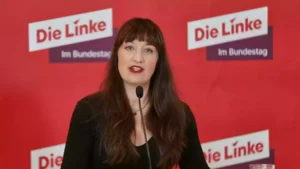 Heidi Reichinnek spricht vor einem roten Hintergrund mit dem Logo der Linken.