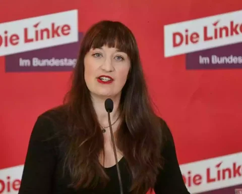 Heidi Reichinnek spricht vor einem roten Hintergrund mit dem Logo der Linken.