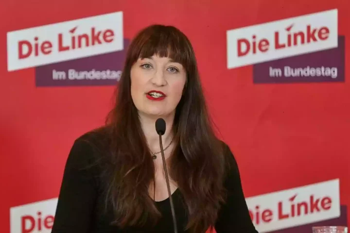 Heidi Reichinnek spricht vor einem roten Hintergrund mit dem Logo der Linken.