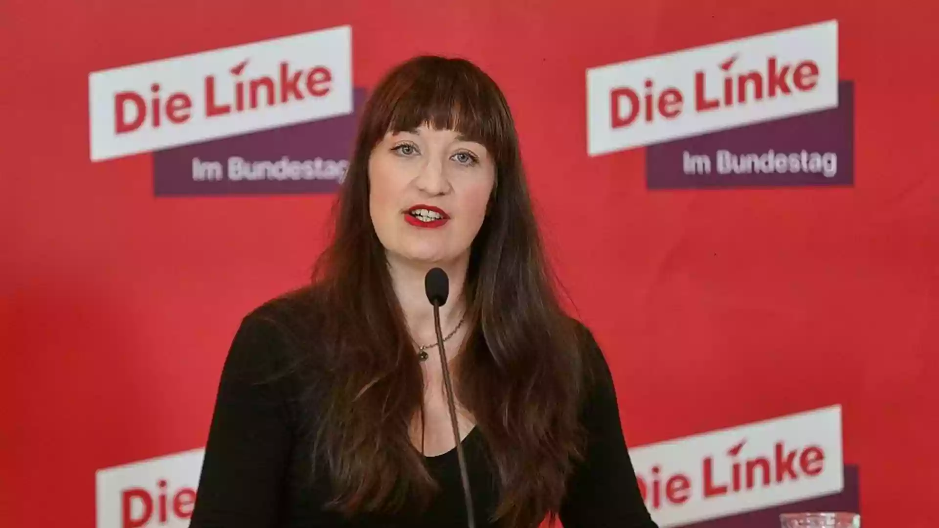 Heidi Reichinnek spricht vor einem roten Hintergrund mit dem Logo der Linken.