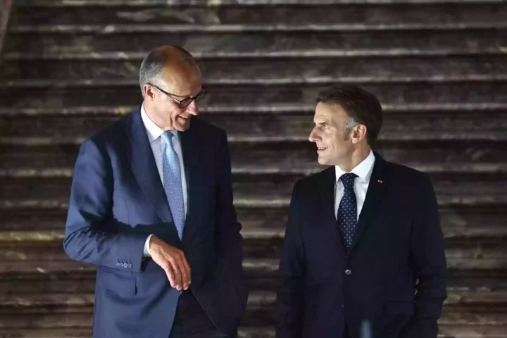 Friedrich Merz und Emmanuel Macron stehen nebeneinander und sprechen bei einem formellen Termin.