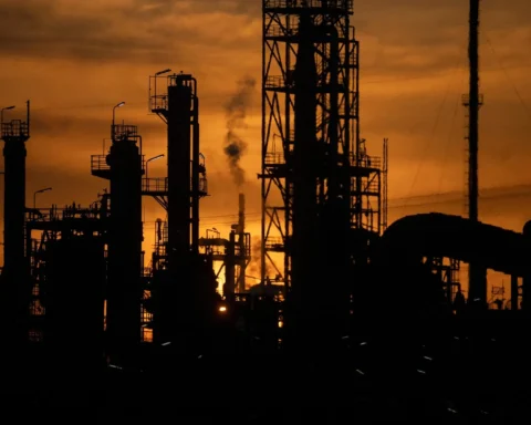 Silhouette einer Raffinerie bei Sonnenuntergang mit Schloten und Industrieanlagen.
