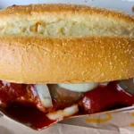 Ein McRib-Sandwich in einer McDonald’s-Verpackung, mit Barbecue-Sauce und Zwiebeln.