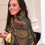 Vanessa Emde lächelt in einem Innenraum und hält ein Smartphone in der Hand.