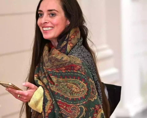 Vanessa Emde lächelt in einem Innenraum und hält ein Smartphone in der Hand.