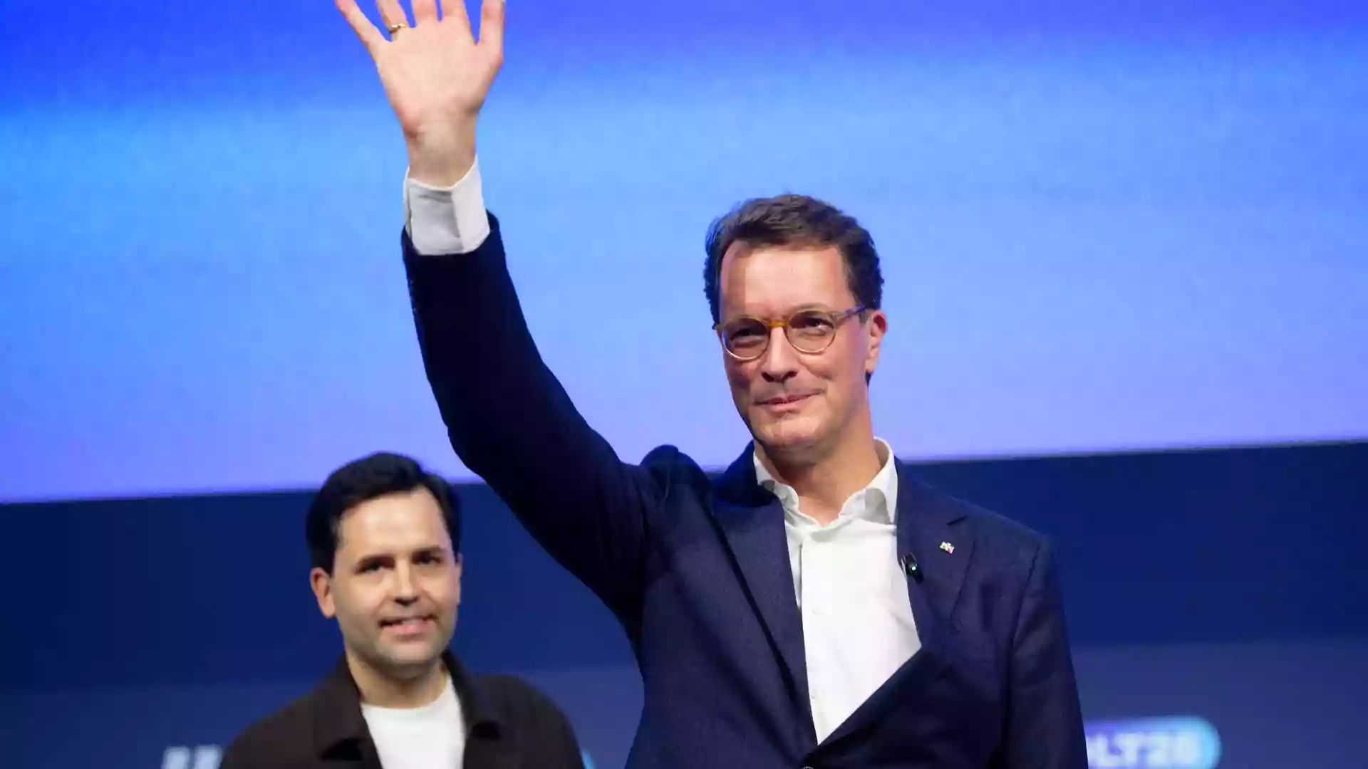 Wüst attackiert Linke und AfD beim Deutschlandtag der Jungen Union 1 Hendrik Wüst winkt auf einer Bühne vor blauem Hintergrund.