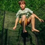Ein Junge springt auf einem Trampolin im Garten.