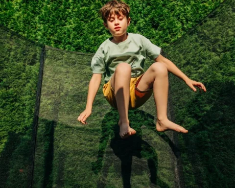 Ein Junge springt auf einem Trampolin im Garten.